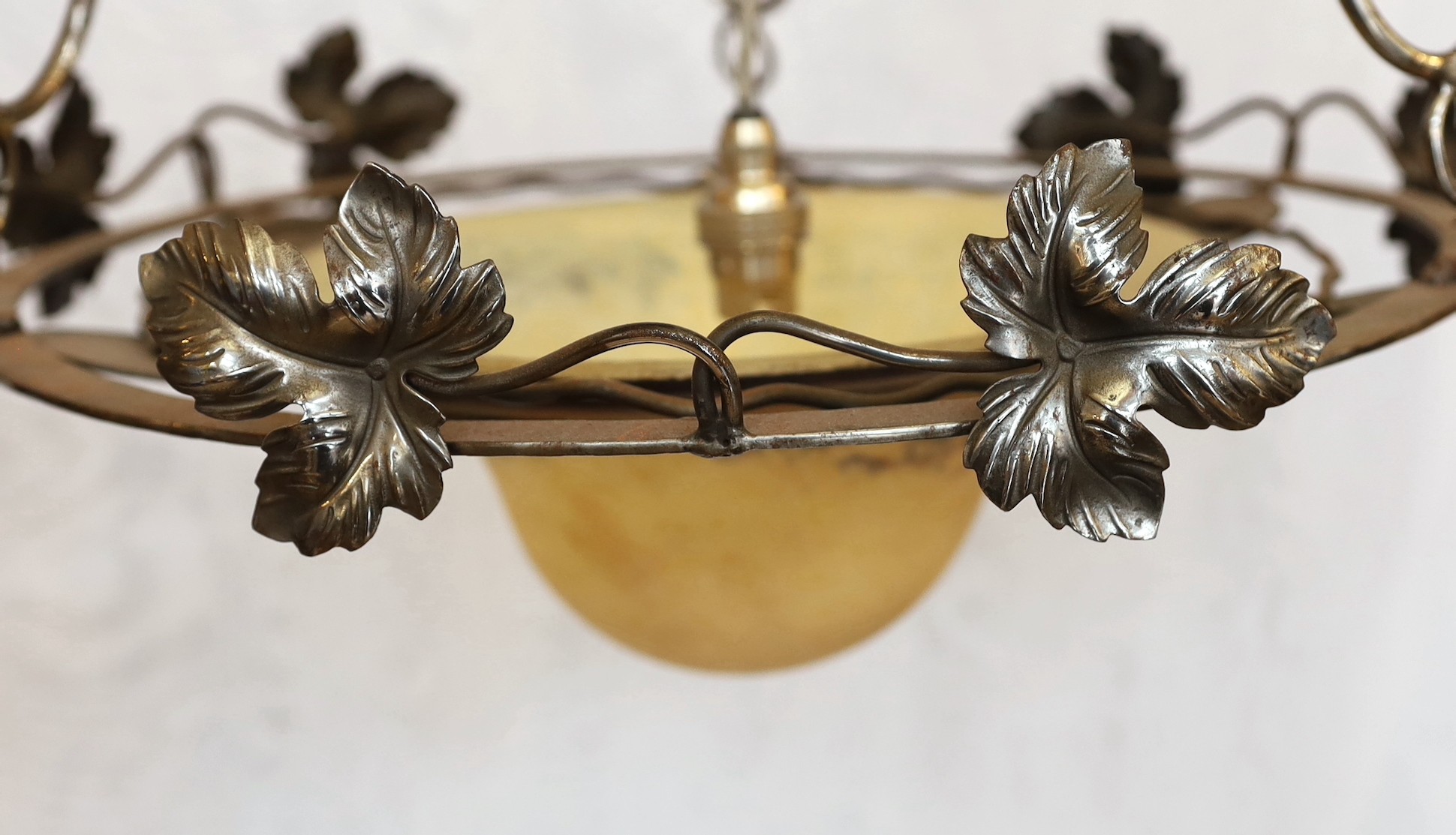A 1920's-30's French polished wrought iron and marbled glass light fitting decorated with foliate motifs, drop 90cm, width 40cm